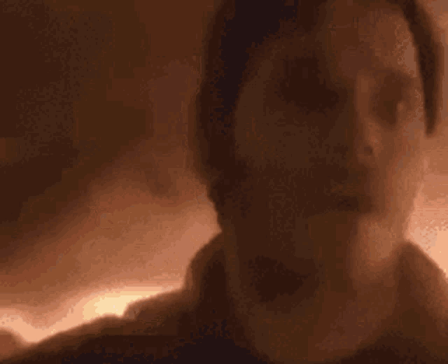 a blurry picture of a woman 's face in a dark room with a light behind her .