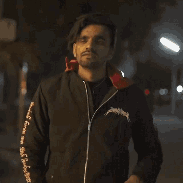 a man wearing a black jacket that says " supreme " on the sleeves