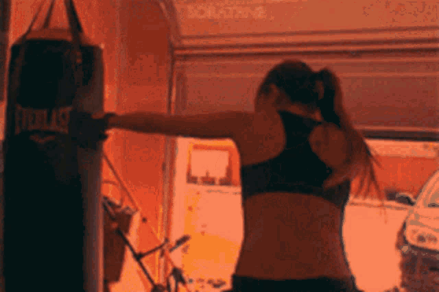 a woman is hitting an everlast punching bag in a garage