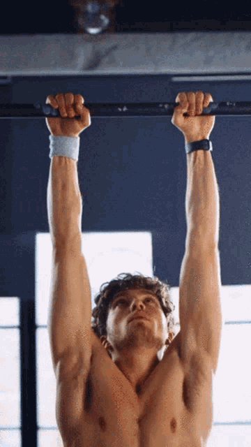 a shirtless man is doing a pull up exercise