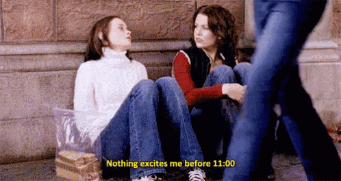 two women are sitting on the sidewalk next to each other .