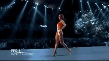 a woman in a swimsuit is walking down a runway at a beauty pageant .