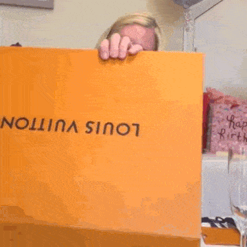 a woman is sitting at a table with a box that says louis vuitton on it