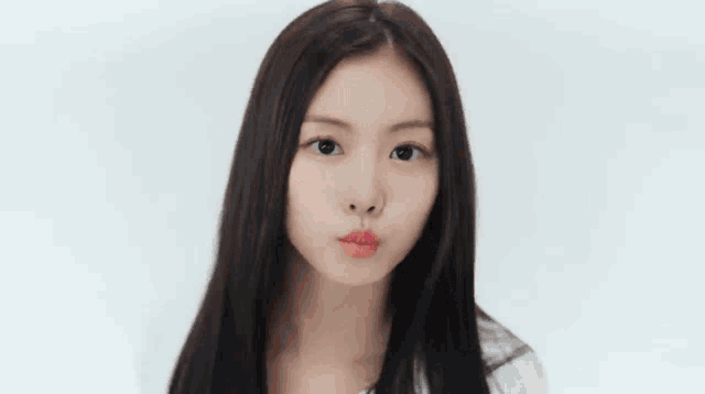 a woman with long black hair is blowing a kiss with her mouth open .