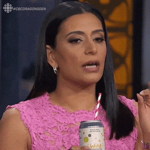 a woman in a pink dress is drinking from a can of wild fermented lemonade