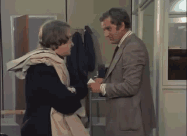 a man in a suit and tie is standing next to a woman in a coat .