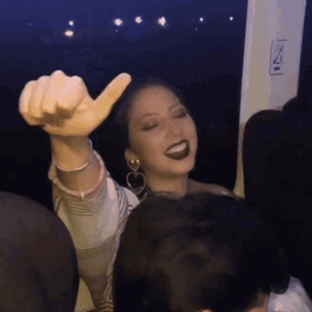 a woman giving a thumbs up in front of a sign that says exit