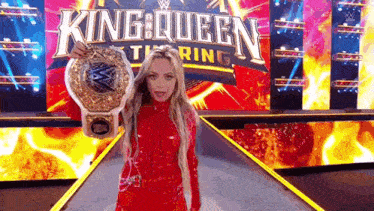 a woman in a red dress is holding a wrestling championship belt while standing on a stage .