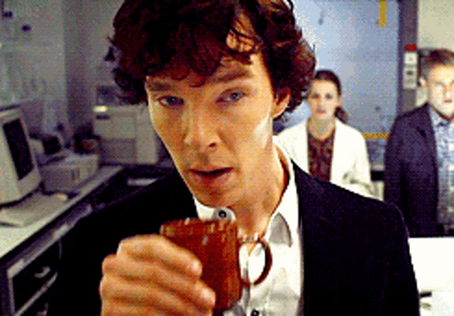 a man in a suit is holding a coffee mug in his hand