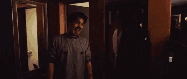 a man with a beard is standing in a dark room screaming .