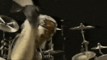 a man is playing drums in a dark room