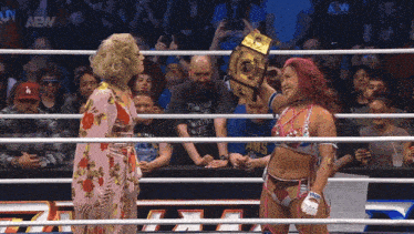 two women are standing in a wrestling ring with a sign that says aew on it