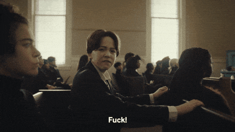 a woman in a suit sitting in a church with the words " fuck " on the bottom