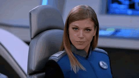 a woman is sitting in a chair with a badge on her chest that says ' captain ' on it