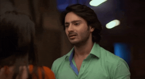 a man in a green shirt is talking to a woman in an orange shirt