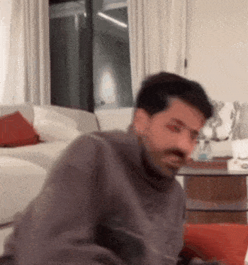 a man is sitting on a couch in a living room looking at the camera .