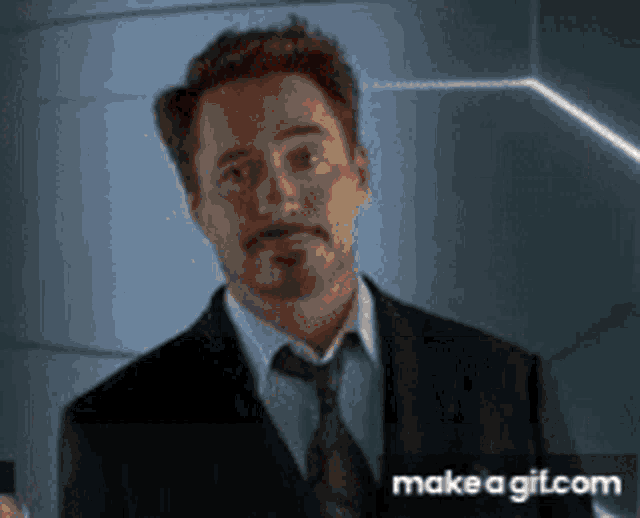 robert downey jr. is wearing a suit and tie and looking at the camera .