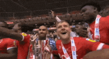 a group of soccer players holding a trophy in a stadium