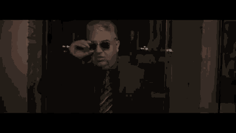 a man in a suit and tie is standing in a dark room talking .