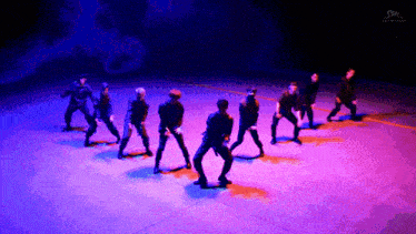 a group of men are dancing on a stage with a sm logo in the corner
