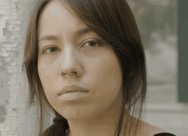 a woman with long brown hair looks at the camera