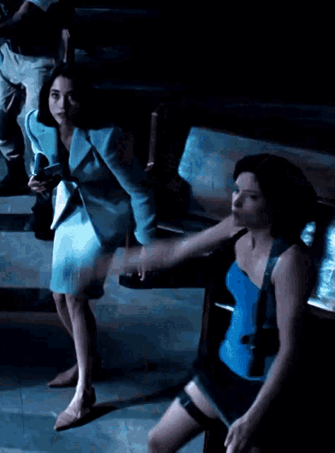 a woman in a blue dress is holding the leg of another woman in a blue top