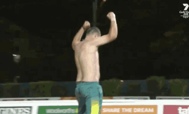 a shirtless man is standing in front of a wall that says share the dream