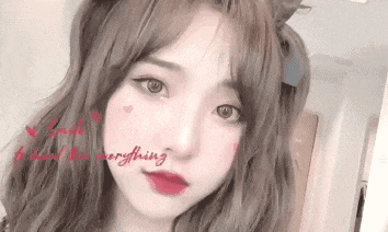 a close up of a girl 's face with a bow in her hair and the words `` everything '' written on her face .