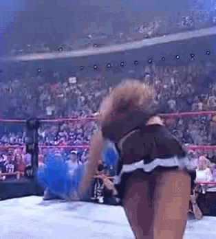 a woman in a wrestling ring with a crowd behind her