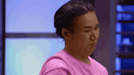 a woman in a pink shirt is sitting in front of a blue wall .
