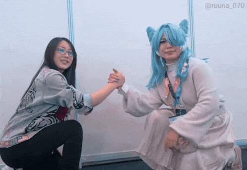a woman in a blue wig holds hands with another woman in a white dress