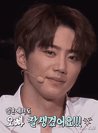 a young man wearing a white shirt and a microphone is looking at the camera .