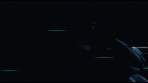 a man with green hair looks at the camera in a dark room