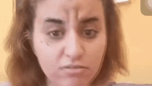 a woman is making a funny face with her eyes closed and a tattoo on her forehead .
