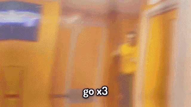 a man in a yellow hoodie is holding a gun and says go x3 in a hallway