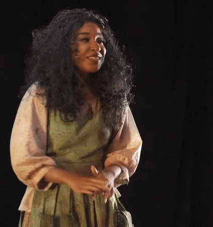 a woman with long curly hair and a green dress is smiling
