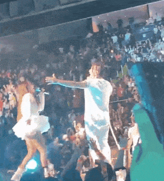 a man and a woman are dancing on a stage in front of a crowd of people .