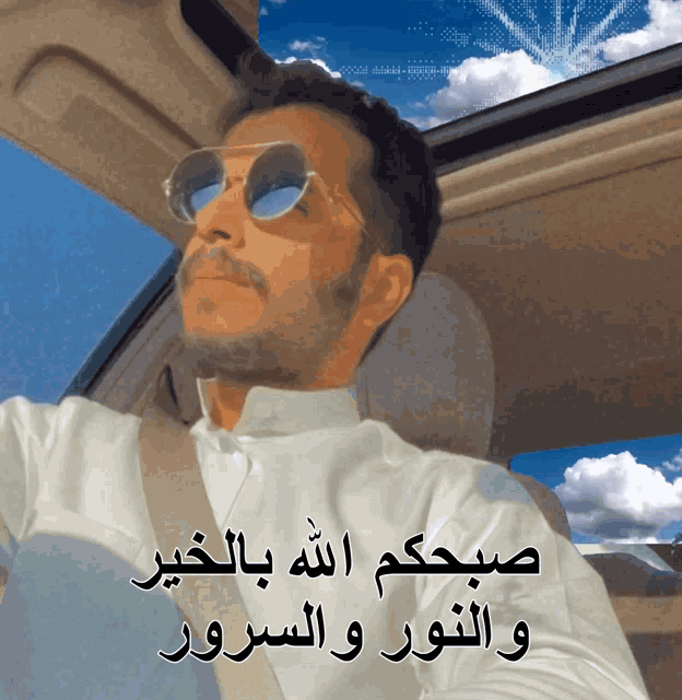 a man wearing sunglasses is sitting in a car with arabic writing on the side