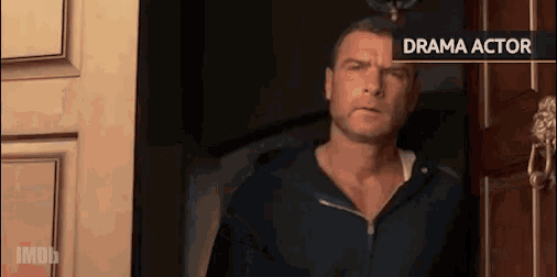 a man in a black hoodie is standing in front of a door with a sign that says drama actor .