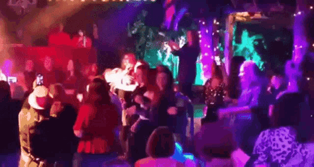 a large group of people are dancing at a party in a club .