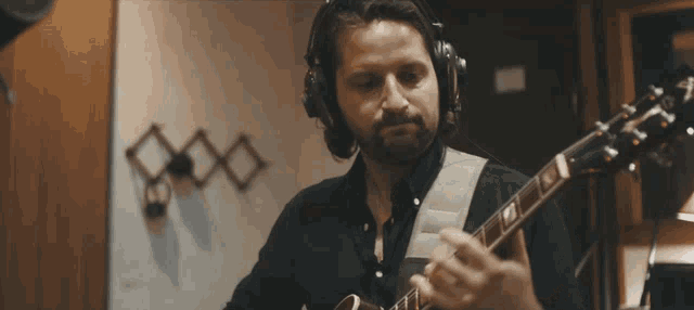 a man wearing headphones playing a guitar