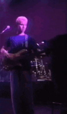 a man is playing a guitar and singing into a microphone on a stage
