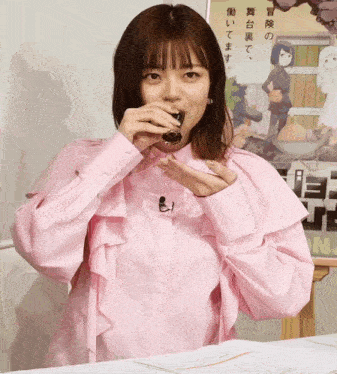a woman in a pink shirt drinking from a cup