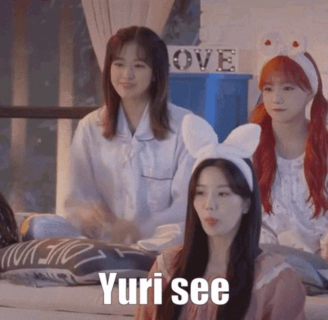 a group of girls are sitting on a bed and one of them is wearing a bunny headband .