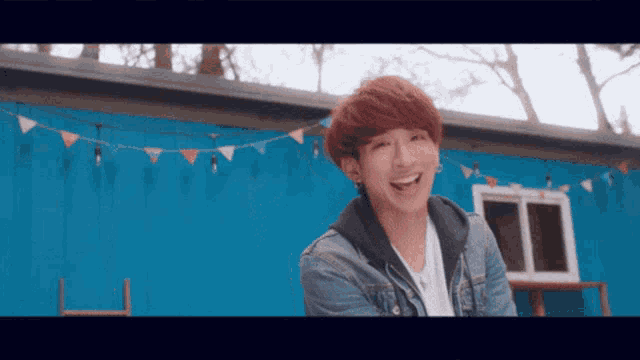 a young man with red hair is smiling in front of a blue wall