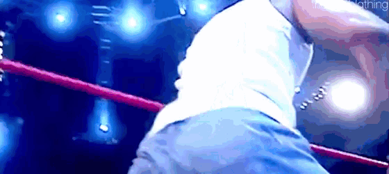 a man is standing in a wrestling ring with a red rope around his waist .