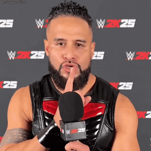 a man with a beard is holding a microphone in front of a wall with w2k25 written on it