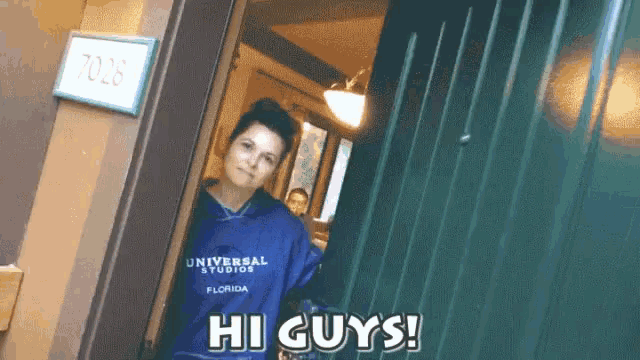 a woman wearing a blue universal studios florida shirt is standing in a doorway