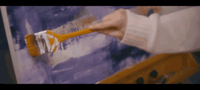 a person is painting with a brush on a canvas