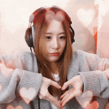 a woman wearing headphones makes a heart with her hands
